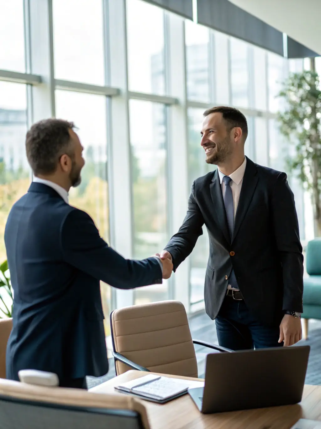 A professional advisor in a suit, smiling and shaking hands with a client in a modern office setting, symbolizing trust and partnership in financial planning.